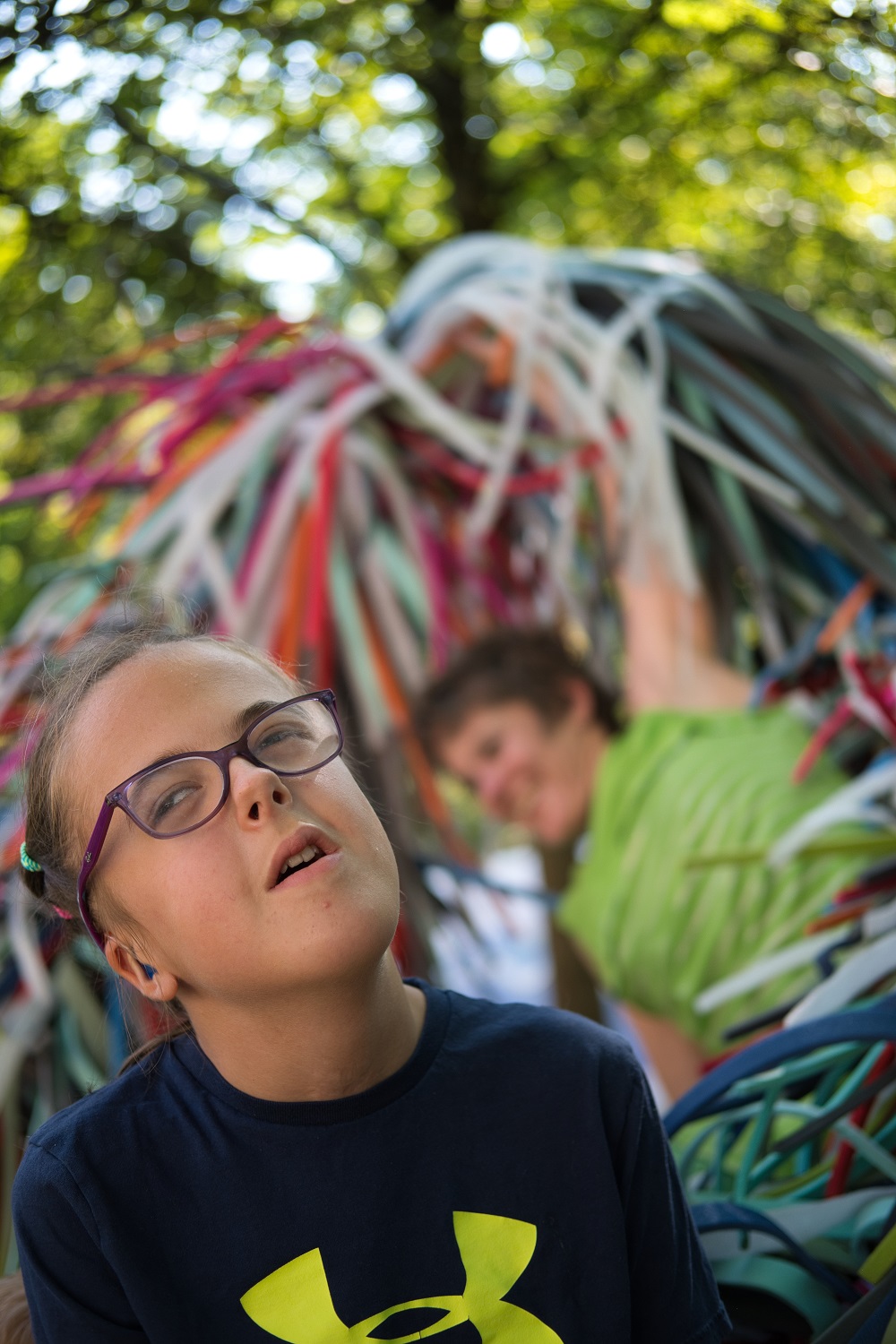 Das Bild zeigt ein Mädchen und eine Frau neben bunten Plastikschlangen