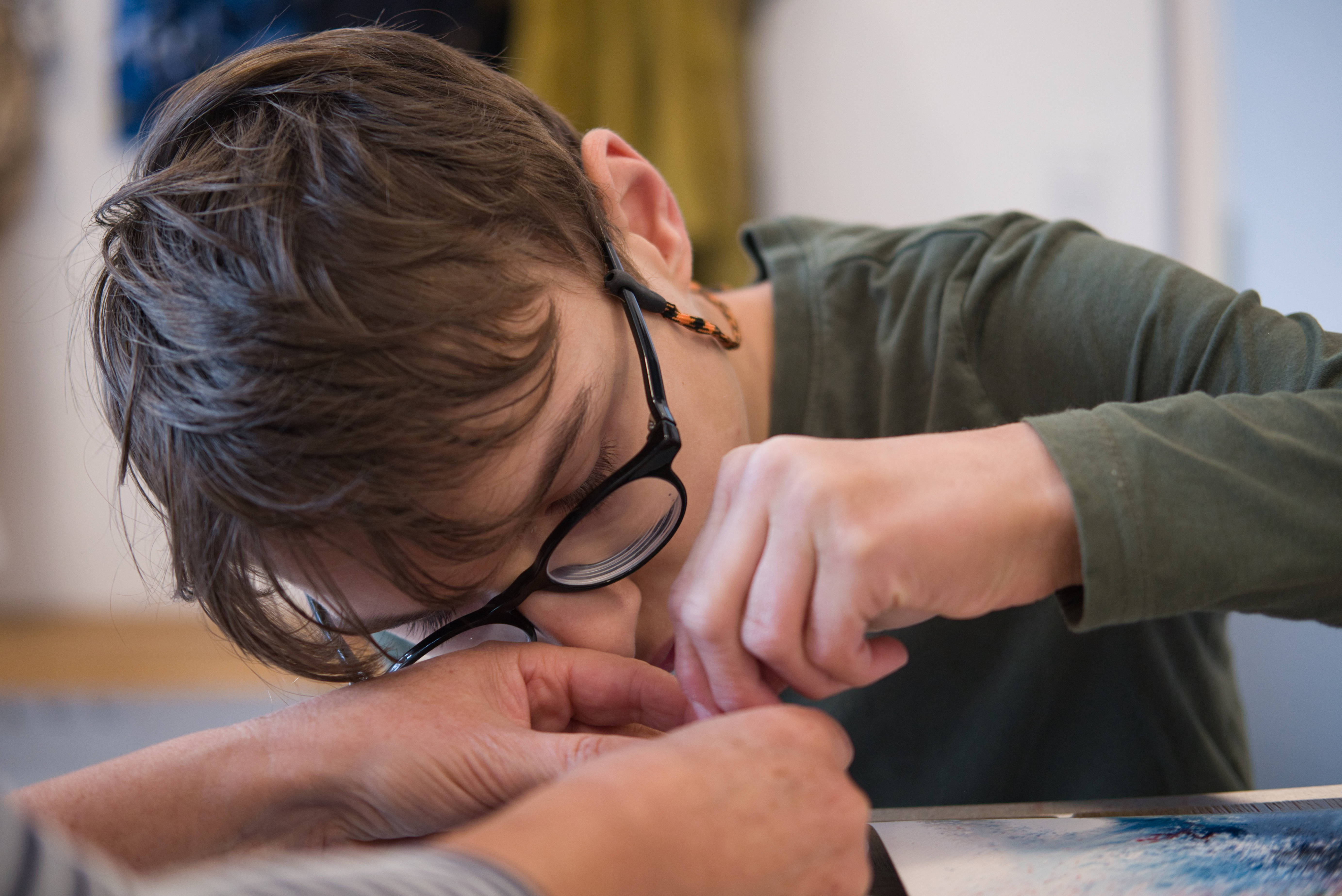 auf dem Bild sieht man einen Jungen mit Brille, der etwas genau ansieht