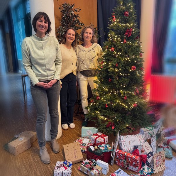 Katrin Tragelehn (Ressortleitung Leben und Wohnen) steht gemeinsam mit den Mitarbeiterinnen, die die Geschenke überbringen vor einem geschmücktem Weihnachtsbaum.