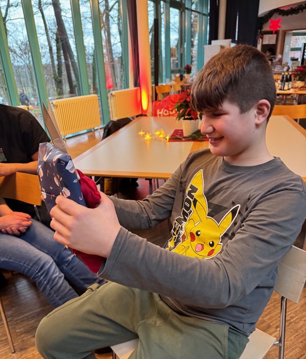 Ein freudiges Kind das ein Weihnachtsgeschenk in Händen hält.