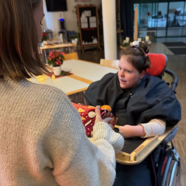 Ein freudiges Mädchen im Rollstuhl, das ein Geschenk erhält.