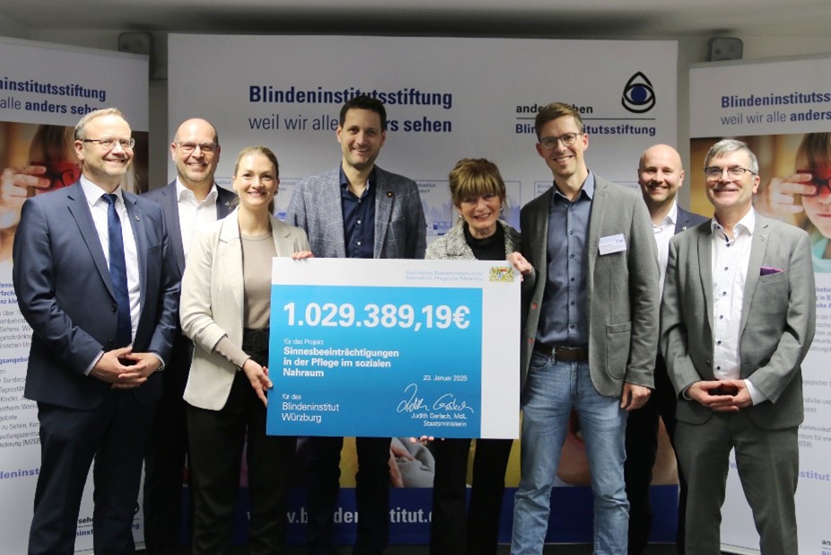 Das Foto zeigt eine Gruppe von acht Personen. In der Mitte wird ein symbolischer Förderscheck gehalten, auf dem die Geldsumme von 1.029.389,19 Euro steht.