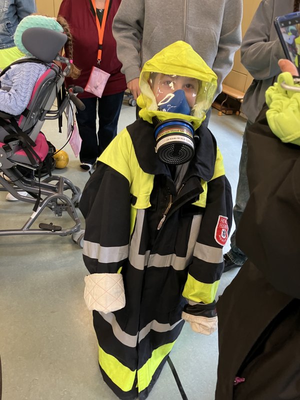 Auf dem Bild sieht man einen Jungen, der einen Feuerwehrschutzanzug trägt.