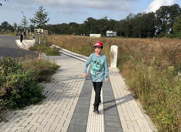 Ein Junge läuft auf dem Blindenleitstreifen auf einem Gehsteig.