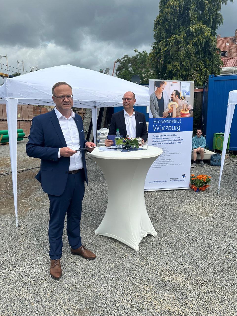 Zwei Männer stehen an einem Stehtisch auf einer Baustelle.