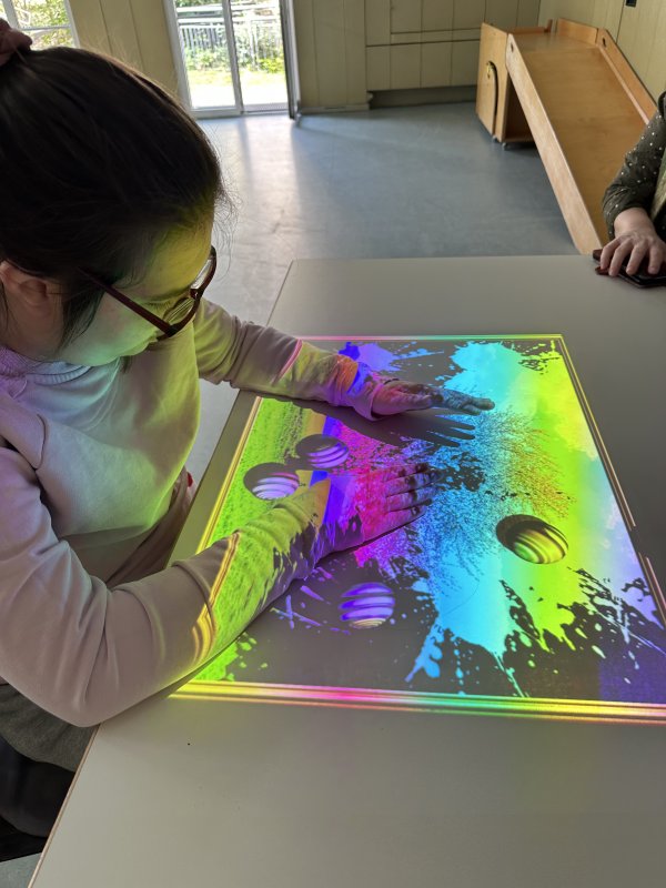 Auf dem Bild sieht man ein Mädchen, das mit einer Projektion auf einer Tovertafel spielt