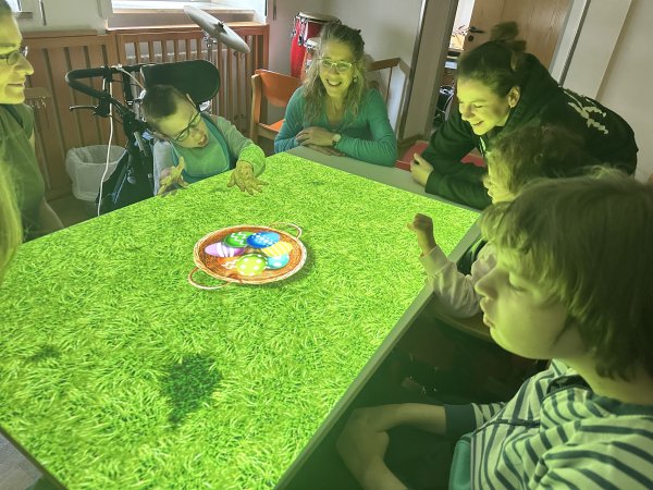 Auf dem Bild sieht man mehrere Kinder und Lehrkräfte, die mit einer Projektion auf der Tovertafel spielen