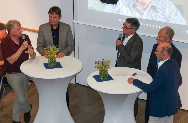Offene Gesprächsrunde von 5 Herren im Anzug, von oben aus fotografiert