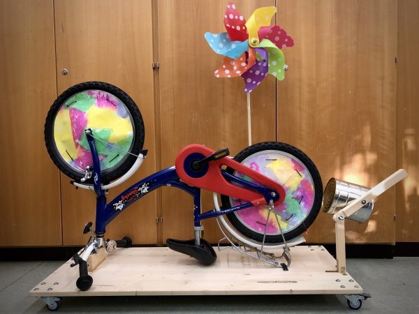 Auf dem Bild sieht man ein Fahrrad. Es steht auf dem Kopf und ist zu einer Krachmaschine umgebaut.