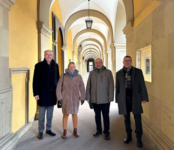 Ein Gruppenbild auf dem drei Männer und eine Frau zu sehen sind. Im Hintergrund sind die Arkaden des Juliusspitals zu sehen.