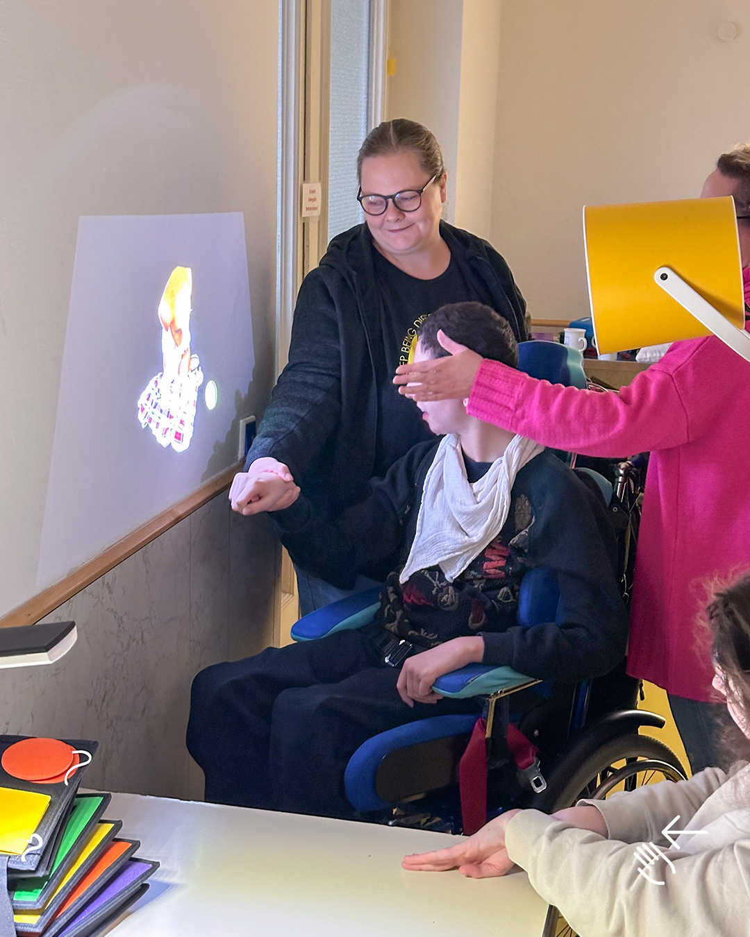 Auf dem Bild sieht man mehrere Menschen vor einem an die Wand projizierten Bild, das  von einer mobilen Tovertafel projiziert wird.