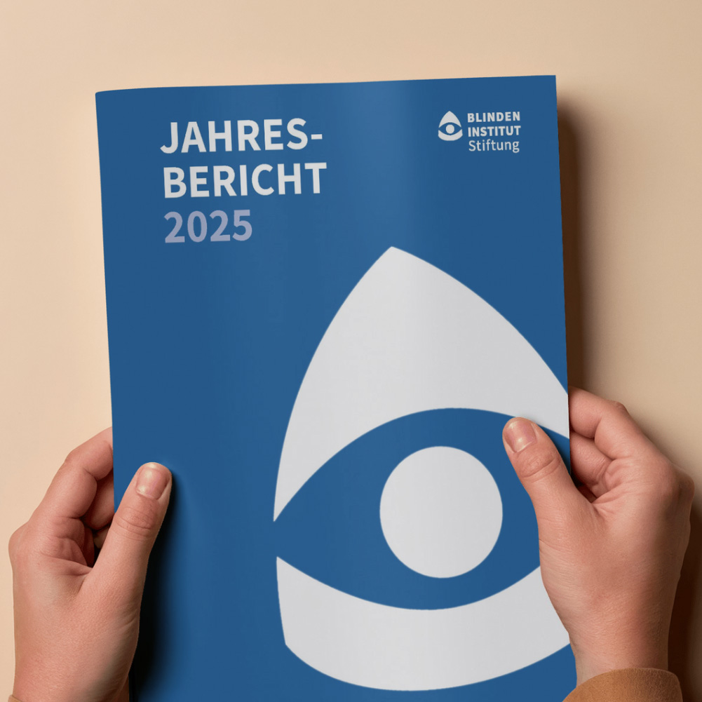 Zwei Hände halten eine blaue Broschüre mit dem Titel „Jahresbericht 2025“ und dem Logo der Blindeninstitutsstiftung.
