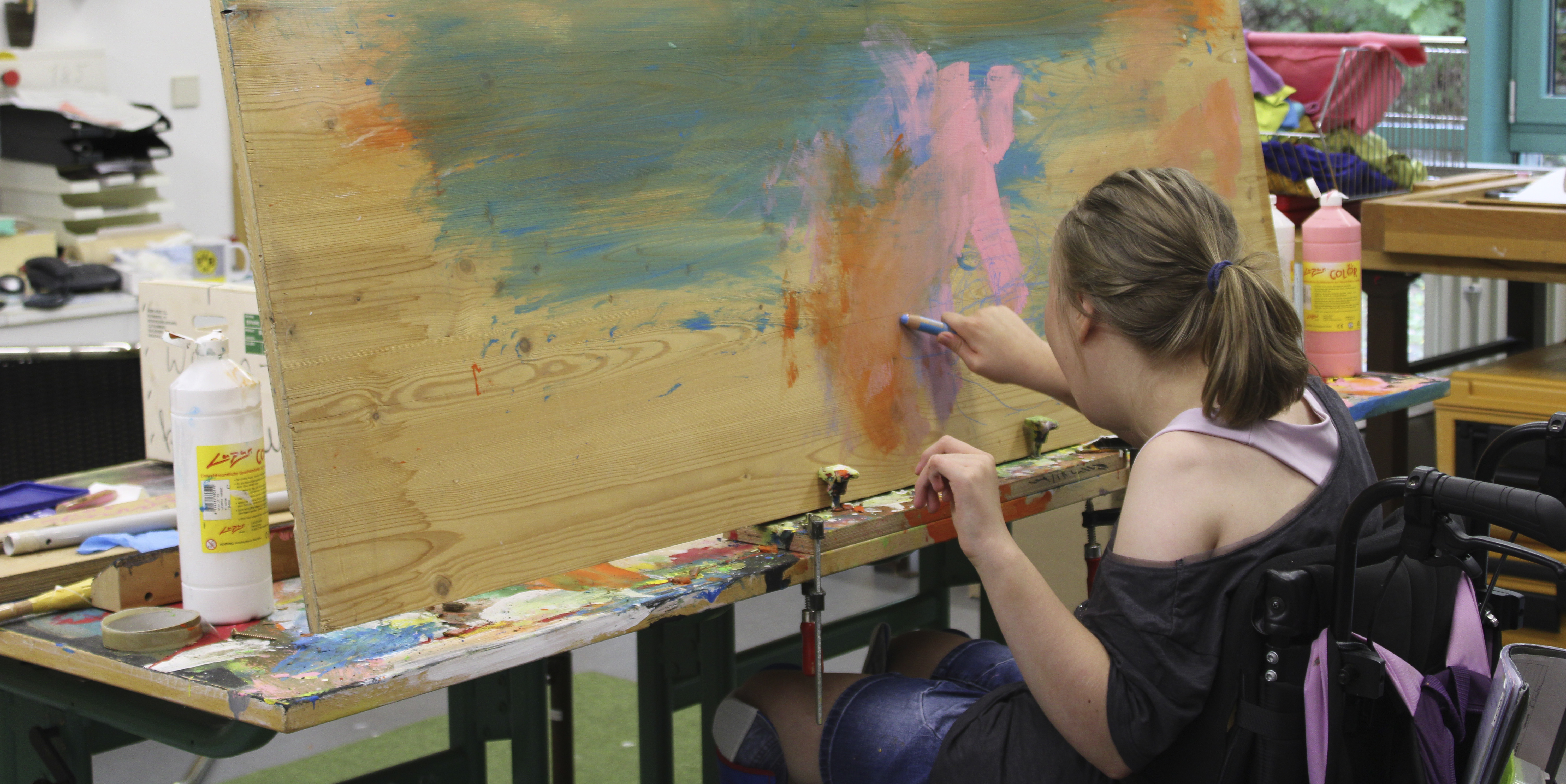 Eine Frau malt an einem Bild an einer Staffelei.