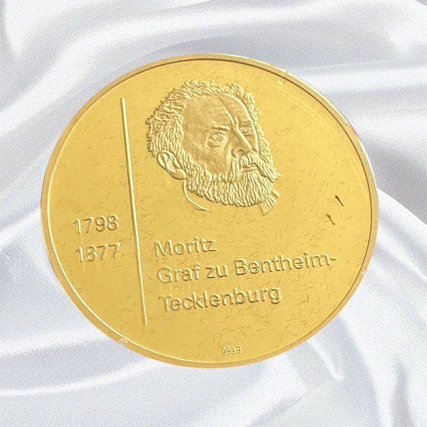 Eine runde goldfarbene Medaille mit dem Porträt eines bärtigen Mannes und der Inschrift „1798–1877 Moritz Graf zu Bentheim-Tecklenburg“.