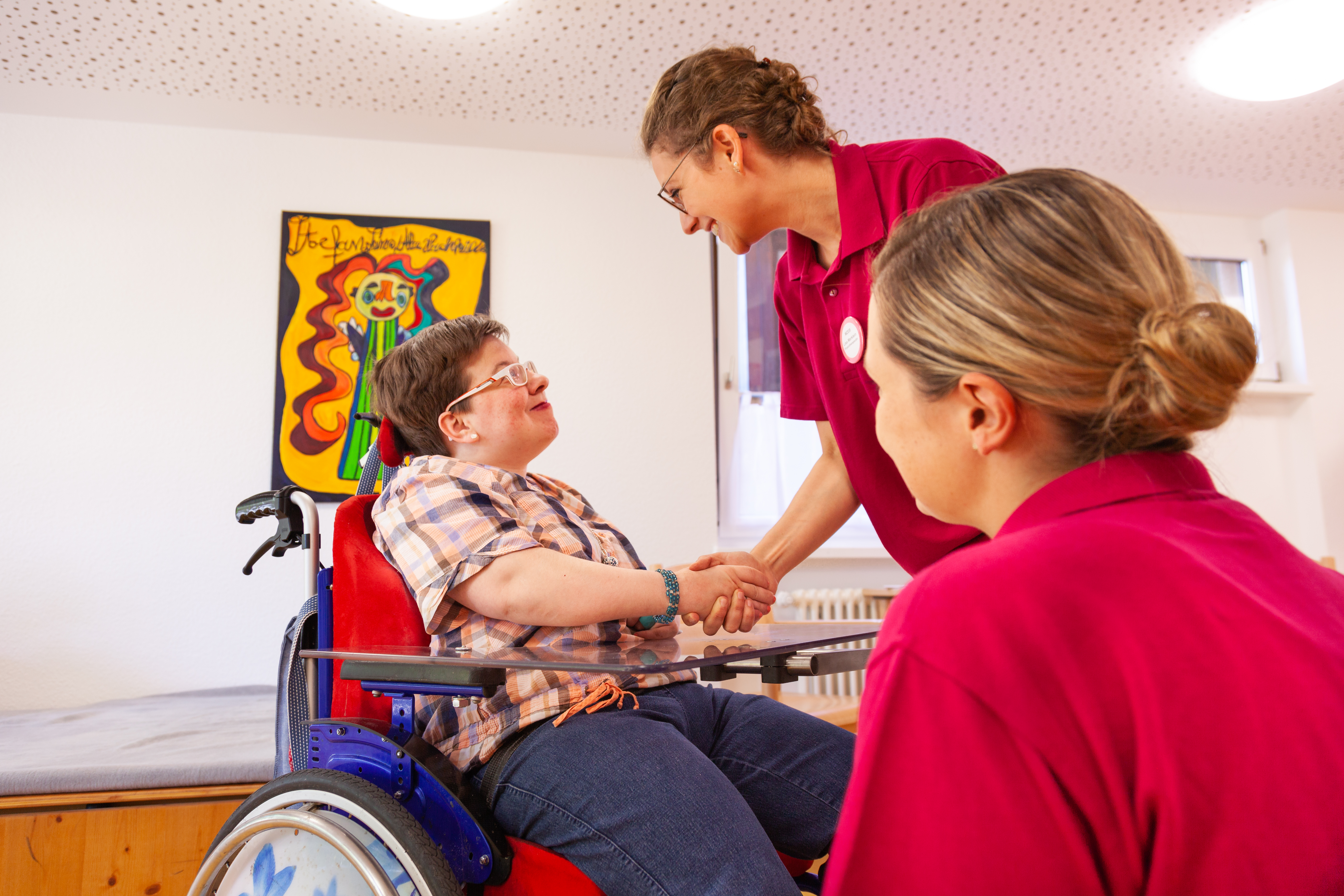 Eine Ärztin und eine Rollstuhlfahrerin schütteln sich lächelnd die Hände.