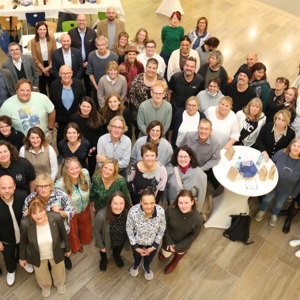 Rund 70 Menschen stehen in einer Gruppe zusammen und schauen zum Fotografen.