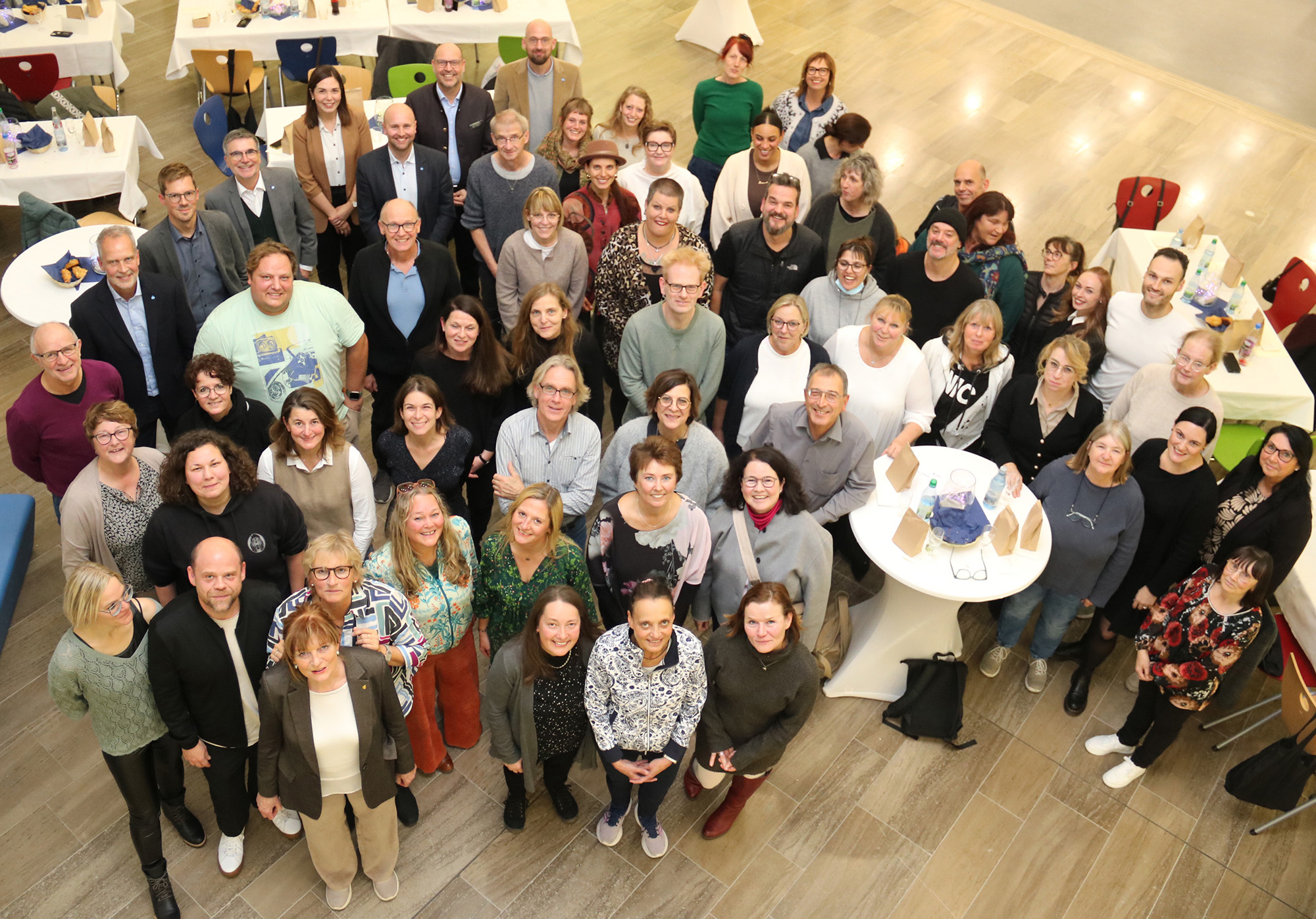 Rund 70 Menschen stehen in einer Gruppe zusammen und schauen zum Fotografen