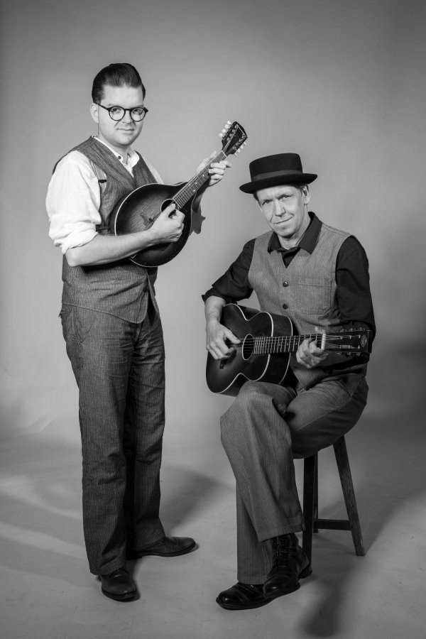 Das Bild zeigt die Band Black Patti. Einen Man mit einer Mandoline in der Hand, der steht und einen mit einer Gitarre in der Hand, sitzend.