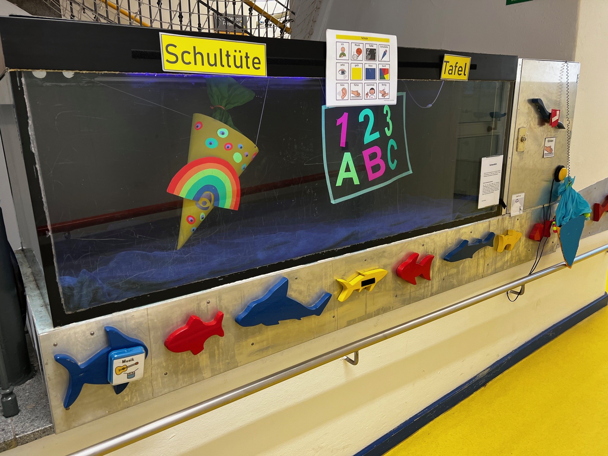 auf dem Bild sieht man ein Aquarium, das mit verschiedenen Gegenständen gefüllt ist, zu, Beispiel Schultüte und ABC-Tafel