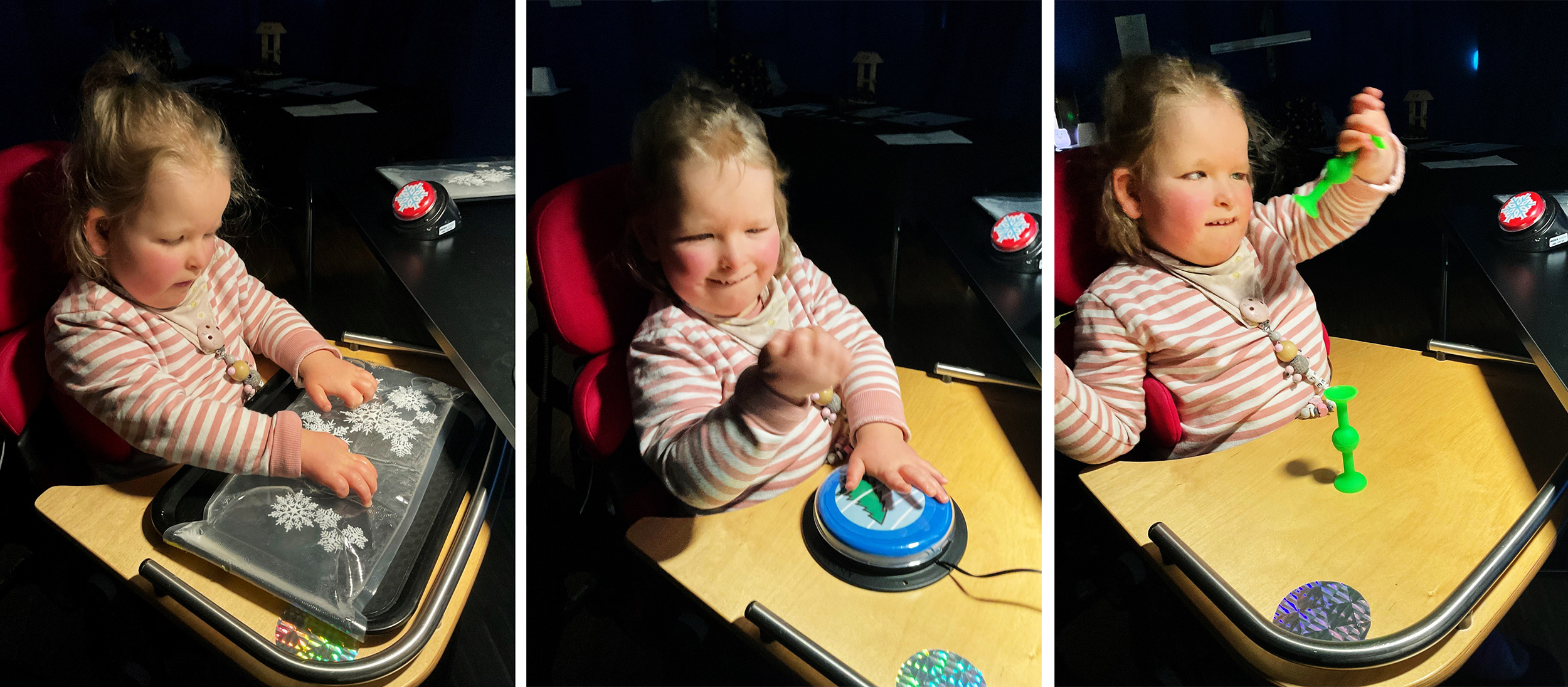 Ein Kind sitzt in einem Rollstuhl mit Ablagebrett und erforscht ein Tablett mit Wassergefülltem Kissen, in dem Schneeflocken schwimmen.  Das Kind trägt gestreifte Kleidung und sitzt nahe an der dekorierten Szene des Sehprojekts.