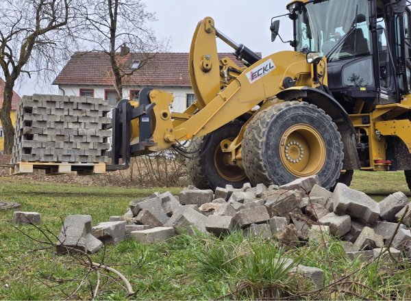 Bagger transportiert Pflastersteine