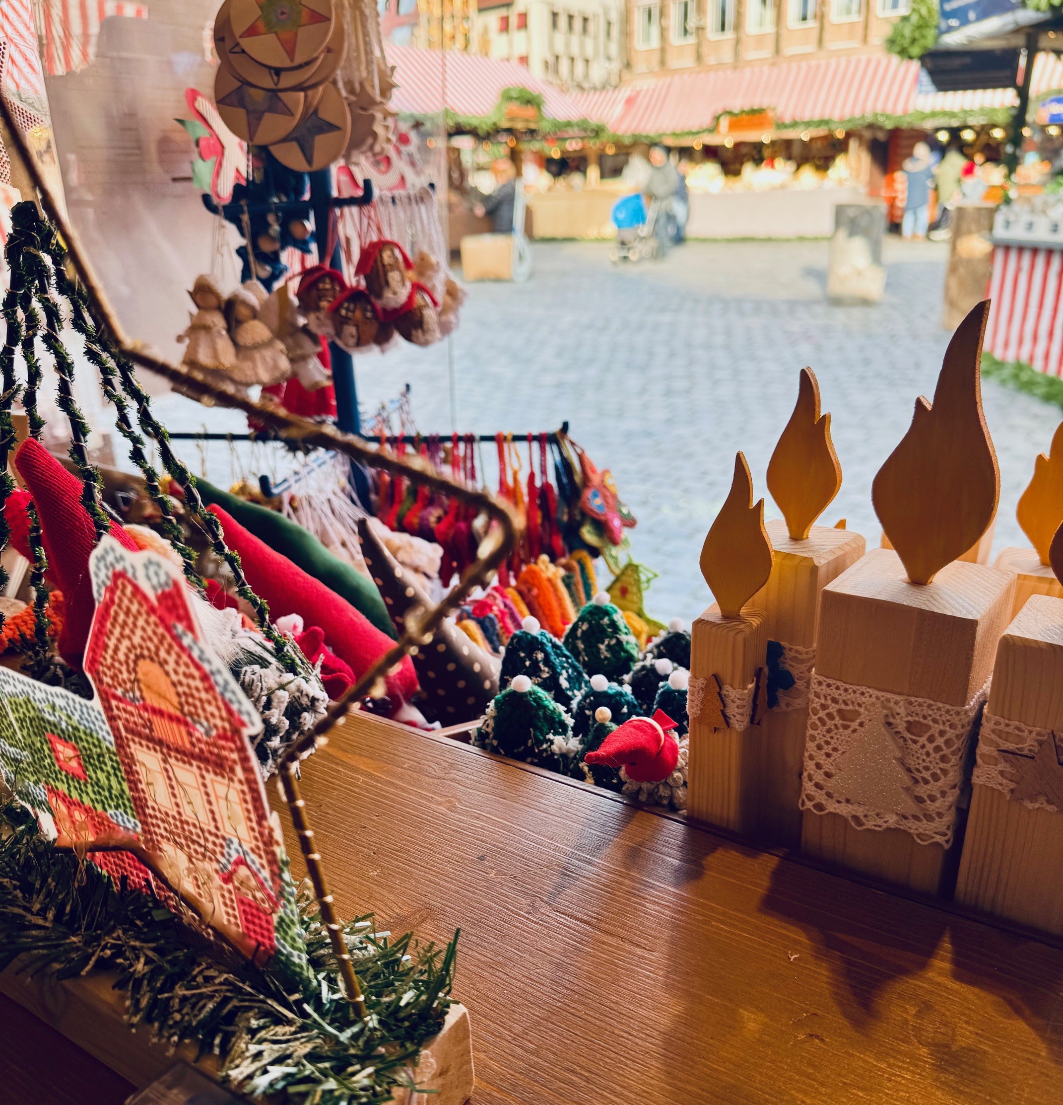 Holztisch mit vielen handgefertigten Weihnachtsdekorationen wie Filzfiguren, kleinen Tannenbäumen und gehäkelten Sternen.