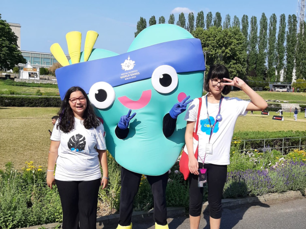 Das Bild zeigt zwei Schüler*innen des Blindeninstituts München mit dem Maskottchen der Special Olympics Unity