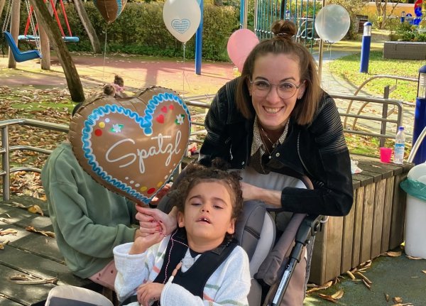 Auf dem Bild sieht man eine Frau und ein Mädchen mit einem Luftballon, auf dem Spatzl steht.