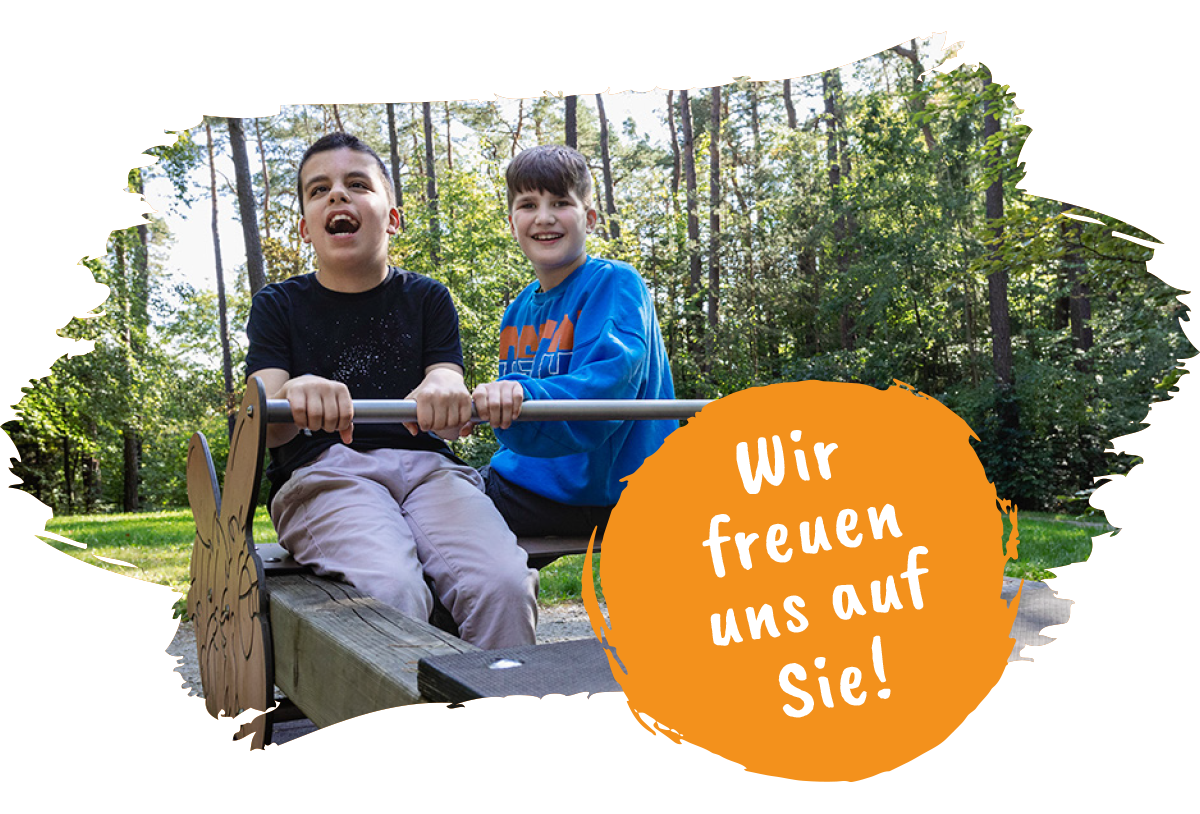 Wir freuen uns auf Sie! Zwei Kinder des Blindeninstituts Rückersdorf sitzen lächelnd auf einer Wippe.l