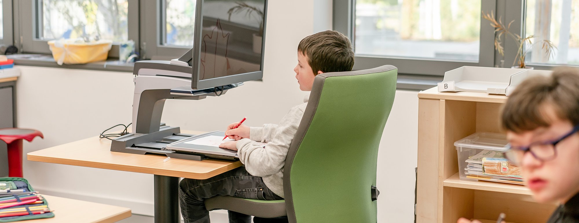 Ein Junge sitzt vor einem Bildschirmlesegerät und malt