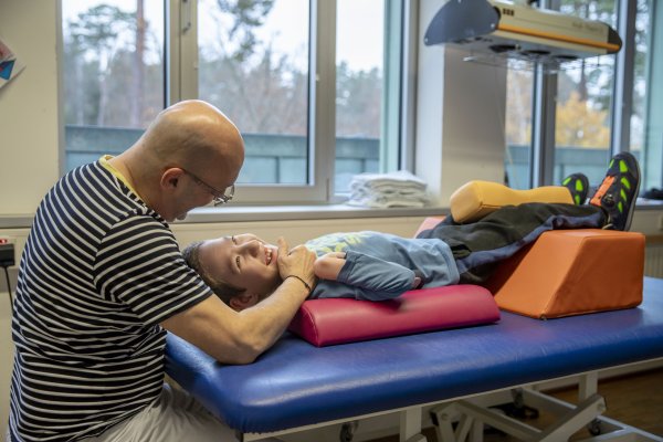 Ein Mitarbeiter der Medizinischen Therapie behandelt einen Jungen auf einer Liege.