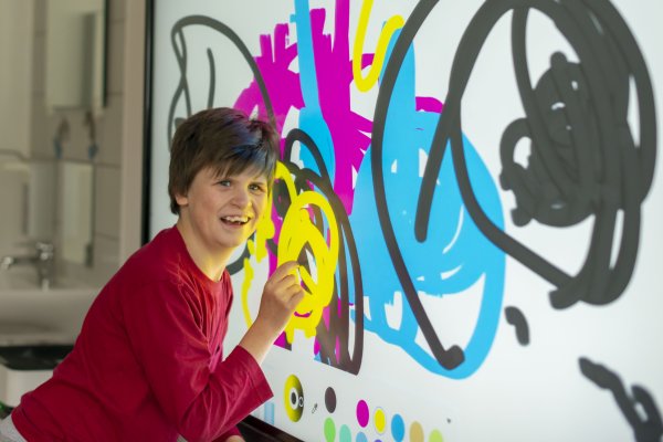 Das Bild zeigt ein Mädchen beim Malen auf einer digitalen Tafel.