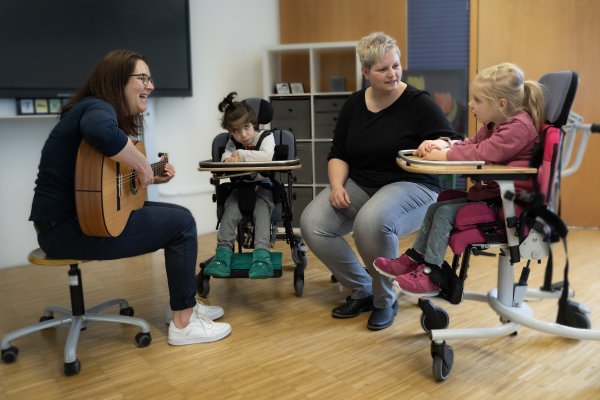 Zwei Pädagoginnen musizieren gemeinsam mit zwei Kindern im Rollstuhl.