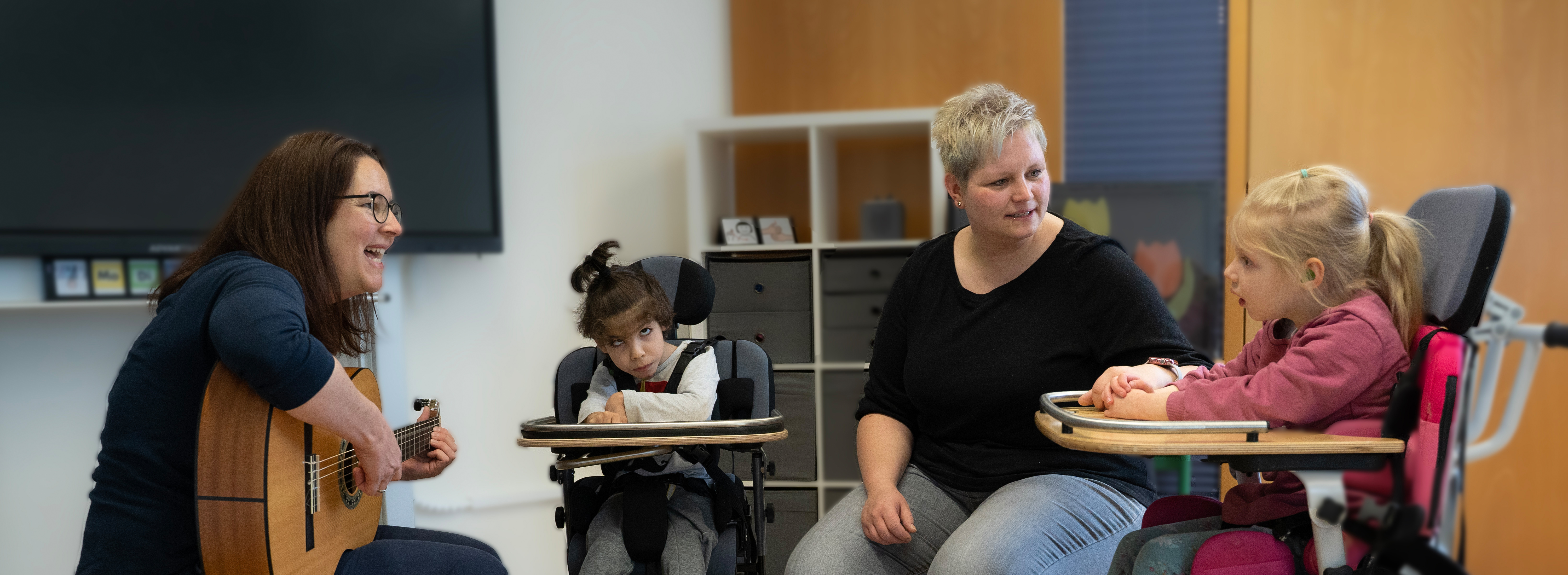 Zwei Pädagoginnen musizieren gemeinsam mit zwei Kindern im Rollstuhl.