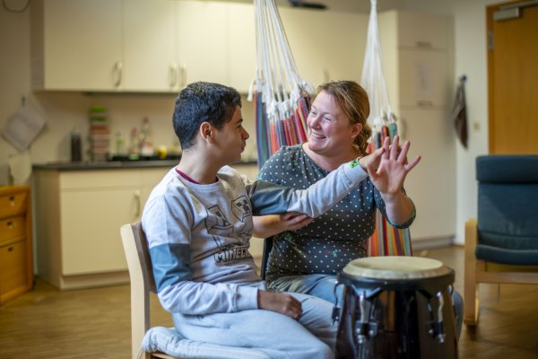 Eine Mitarbeitende des Blindeninstitut Rückersdorf musiziert gemeinsam mit einem Jungen auf der Trommel.